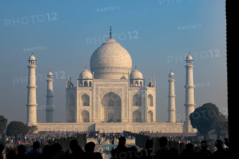 Taj Mahal, the mausoleum built for Mumtaz Mahal by her husband, the Mughal emperor, Shah Jahan. Wonder of the World, a UNESCO World Heritage Site, famous landmark and tourist attraction. View from the gateway with visitors watching and photographing. Winter morning light, clear blue sky. Agra, Uttar Pradesh, India, Asia