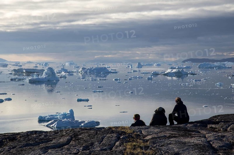Rodebay, Greenland, July 09, 2018: A group of people sitting and looking at icebergs. Rodebay, also known as Oqaatsut is a fishing settlement north of Ilulissat, North America