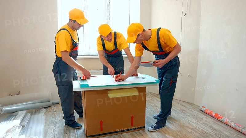 Preparatory phase of house renovation. Working group is studying a plan of apartment. Business professional contractor
