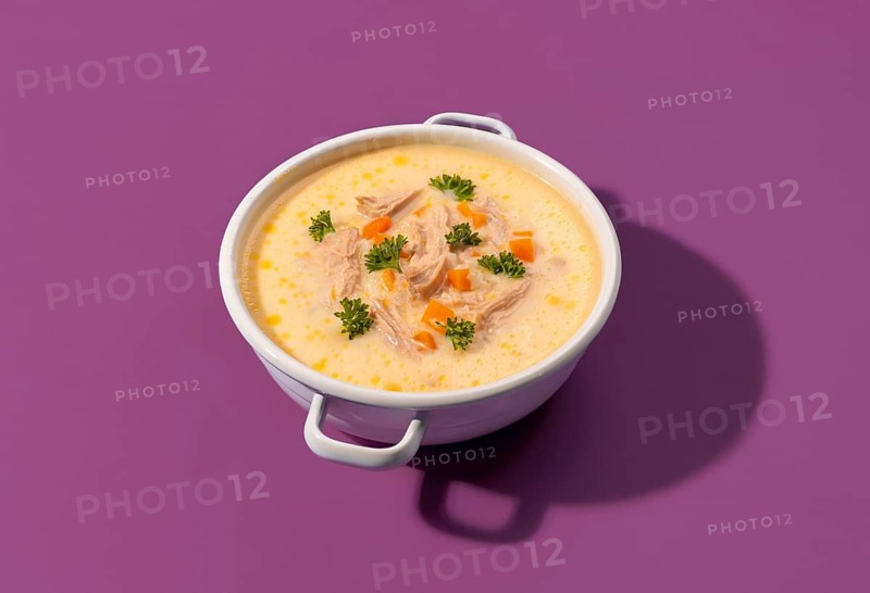 Delicious greek chicken soup with lemon juice and vegetables, in a white enamel bowl, isolated on a colored background