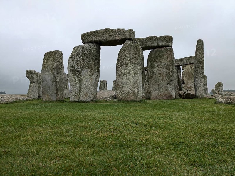 Close-up of Stonehenge with green grass and cloudy sky, emphasizing its ancient and historical nature. Salisbury, England, United Kingdom, Europe