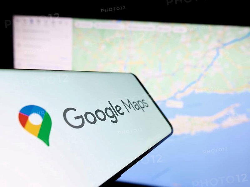 Stuttgart, Germany, 03-10-2023: Smartphone with logo of web mapping platform Google Maps on screen in front of website. Focus on center-right of phone display, Europe