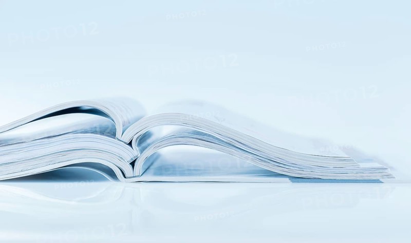 Stack of open magazines in blue tone on white background with copy space