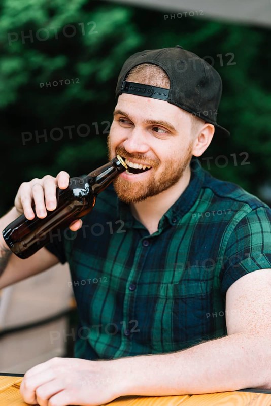 Man opening beer bottle cap with his teeth