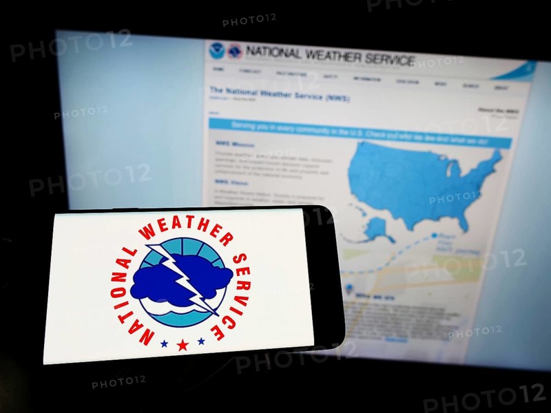 Stuttgart, Germany, 09-30-2022: Person holding cellphone with logo of US agency National Weather Service (NWS) on screen in front of webpage. Focus on phone display, Europe