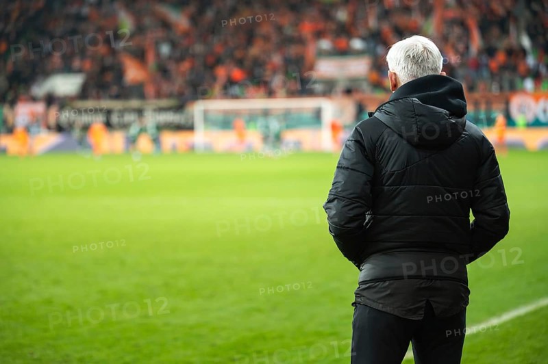 Head coach's back and soccer match at the stadium in the background