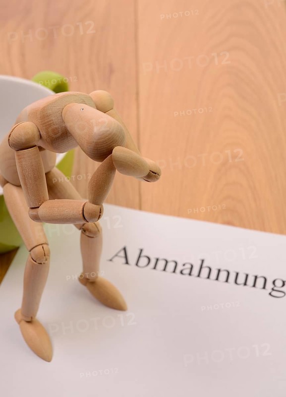 Letter of warning on a table, desperate figure sitting on a cup