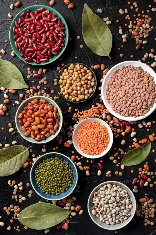 Various legumes, shot from the top on a dark background. Lentils, soybeans, chickpeas, red kidney beans, black-eyed peas and other pulses, a flat lay