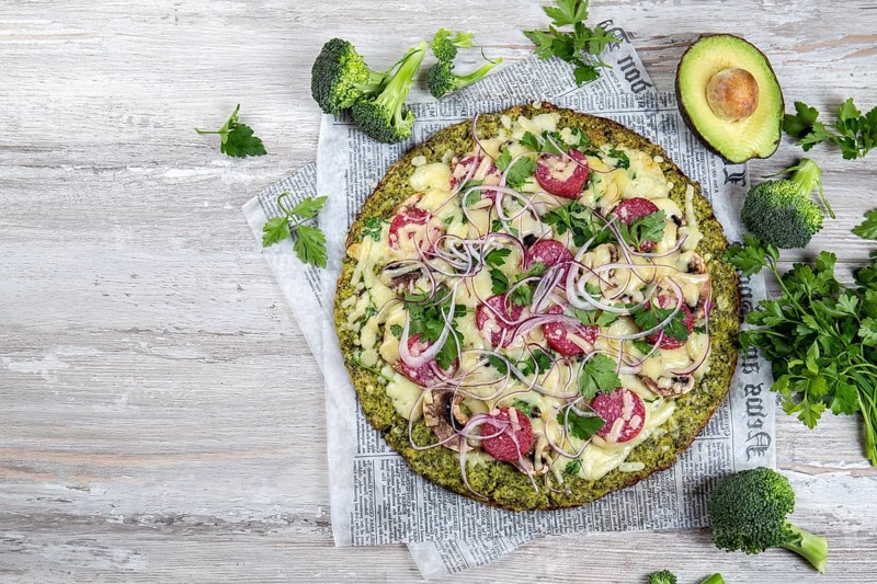 Food, Crust Broccoli base low carbs keto pizza with salami, avocado on vintage newspapper. Top view