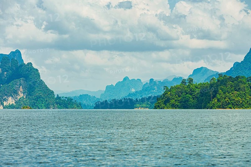 Distant mountains on a cloudy horizon overlook a vast lake, offering a calm natural scene, Cheow Lan Lake, Khao Sok National Park, Thailand, National Park, Khao Sok lake, water, mountains, green, Asia