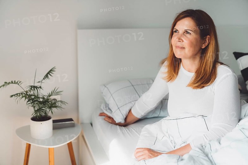 Cheerful happy caucasian woman relaxing at home on her day off work. Adult content woman spending time at home, in her apartment, resting on the couch, having a cup of coffee, feeling good