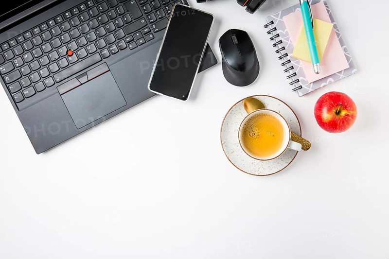 Working place and office desk with coffee, laptop, apple, headset and smarthpone. Flatlay in black tone