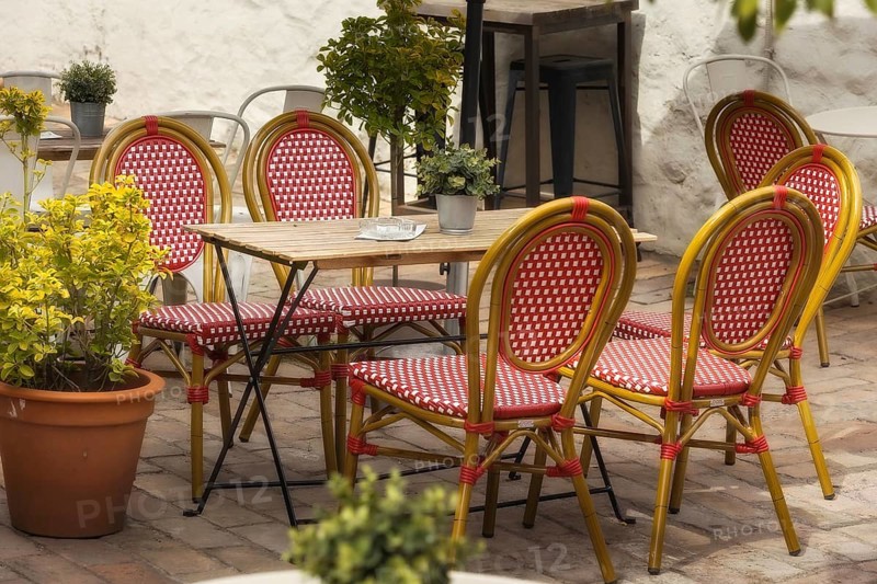 Outdoor empty coffee and restaurant terrace with red and white chairs and table, flowers