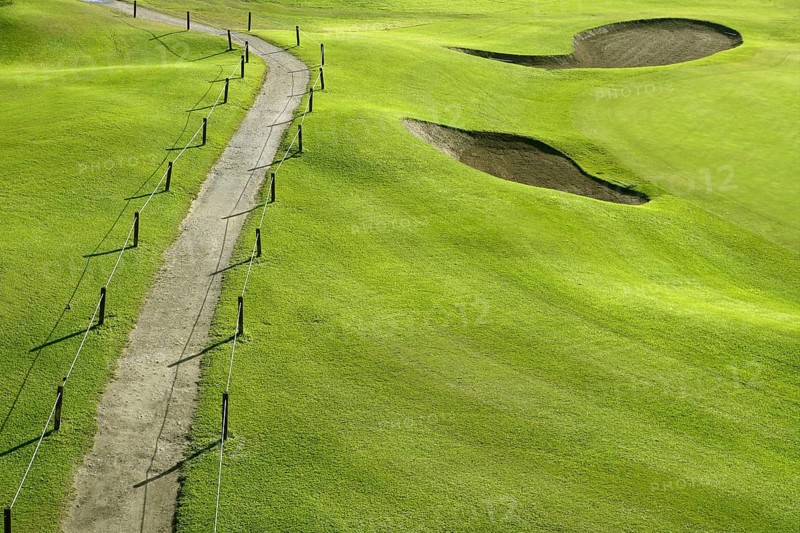 Golf course green grass hill field with holes and track way