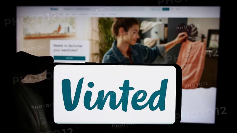 Stuttgart, Germany, 03-17-2024: Person holding cellphone with logo of online secondhand marketplace company Vinted in front of business webpage. Focus on phone display, Europe
