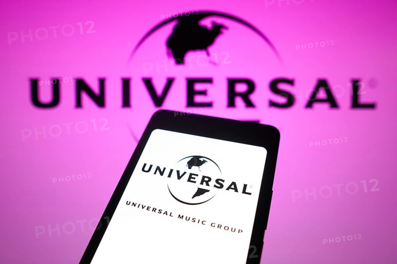 In this photo illustration, the Universal Music Group logo is displayed on a smartphone screen and in the background