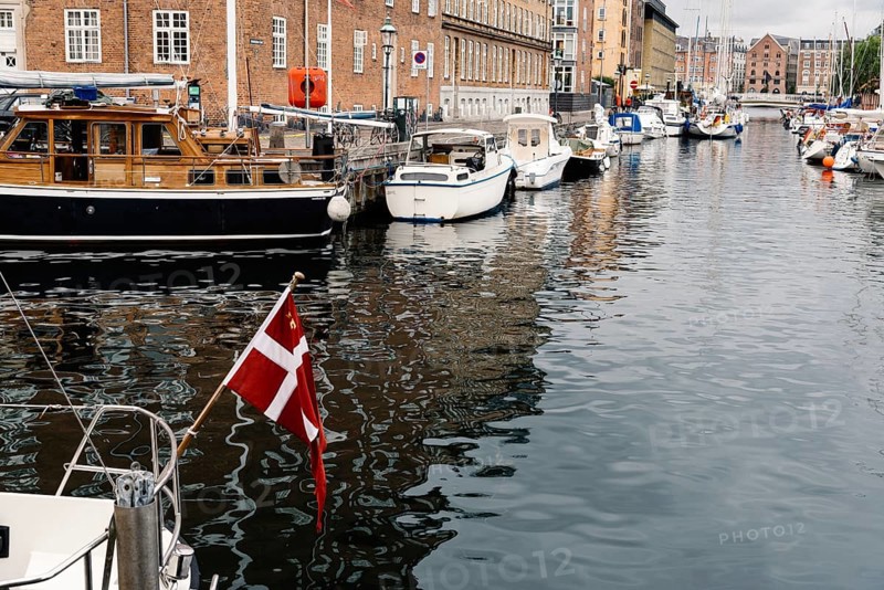 Copenhagen, Denmark, August 12, 2016: Port of Copenhagen with boats and ships moored. Danish flag on foreground, Europe