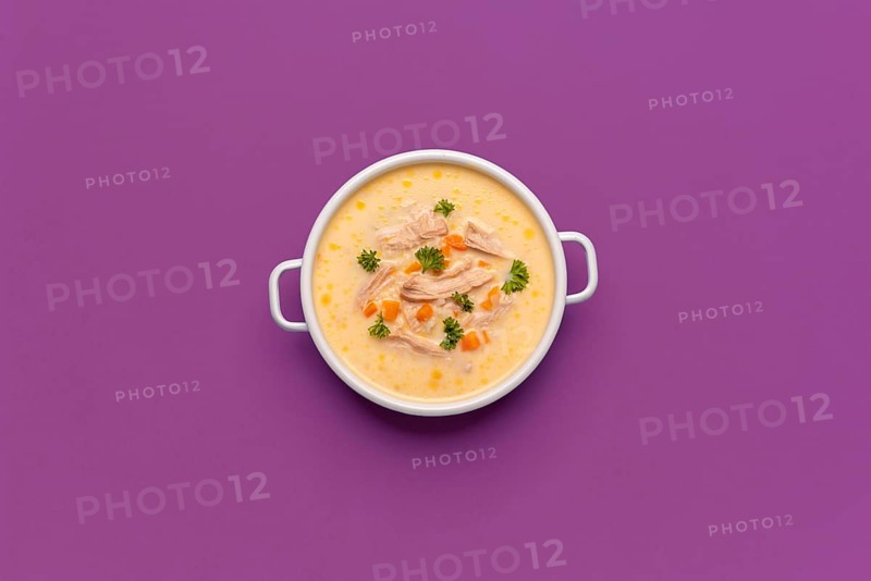 Top view with a bowl of chicken soup, greek recipe with lemon juice and vegetables