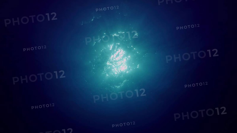 View of sun light from blue abyss, slow motion. Light filters down through blue water. Underwater sun rays in depth ocean. Underwater light, sun light shine under deep water with ripples on surface