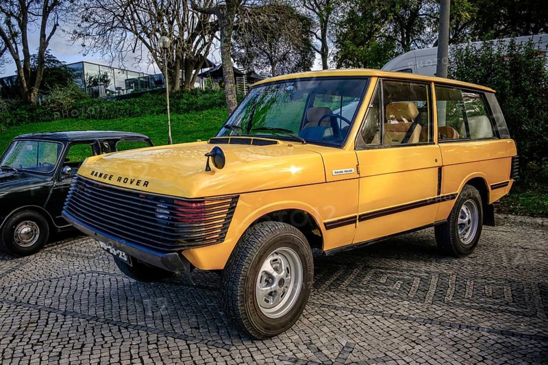 Lisbon, Portugal, Jan 20, 2024: A classic yellow Land Rover Range Rover car with extra front protection detailing parked on a cobblestone road near green park, Europe