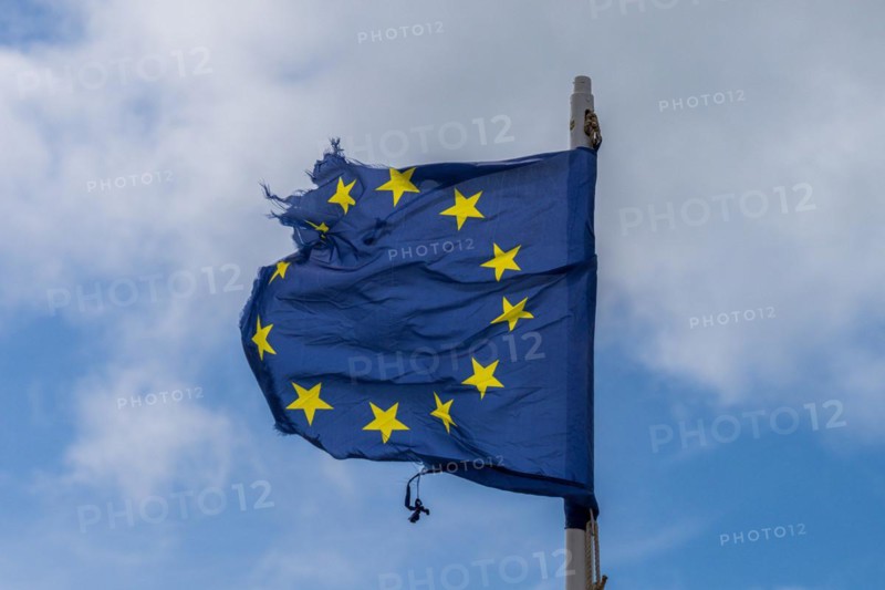 A torn EU flag blows in the wind with a few clouds in the background, seen in Pevensey Bay, East Sussex, England, UK
