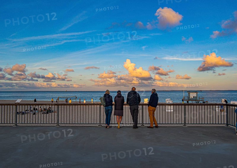 Holidaymakers stand on the promenade in the evening light and look out to sea, Hörnum, Sylt