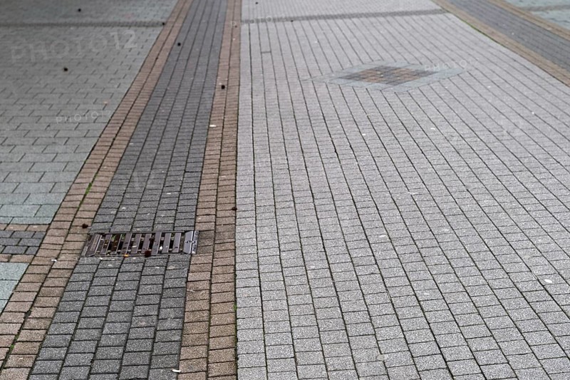 Deserted paved pedestrian zone with gully cover