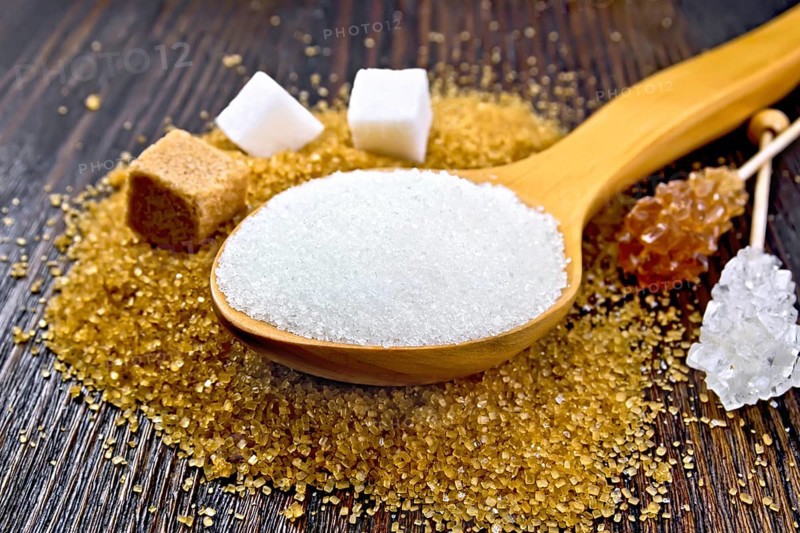 Sugar white and brown in cubes, crystal on a stick and granulated in a spoon on a wooden plank background