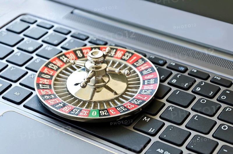 Roulette wheel lying on computer keyboard symbolizing online gambling