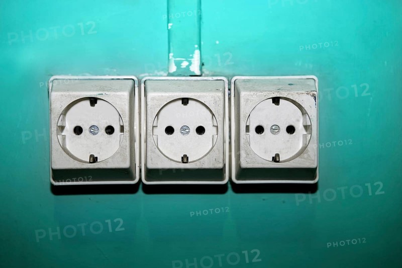 Aged electric plug socket dirty over green wall