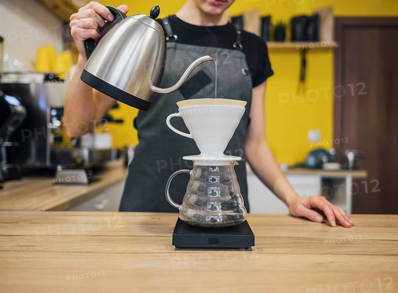 Front view female barista pouring hot water coffee filter
