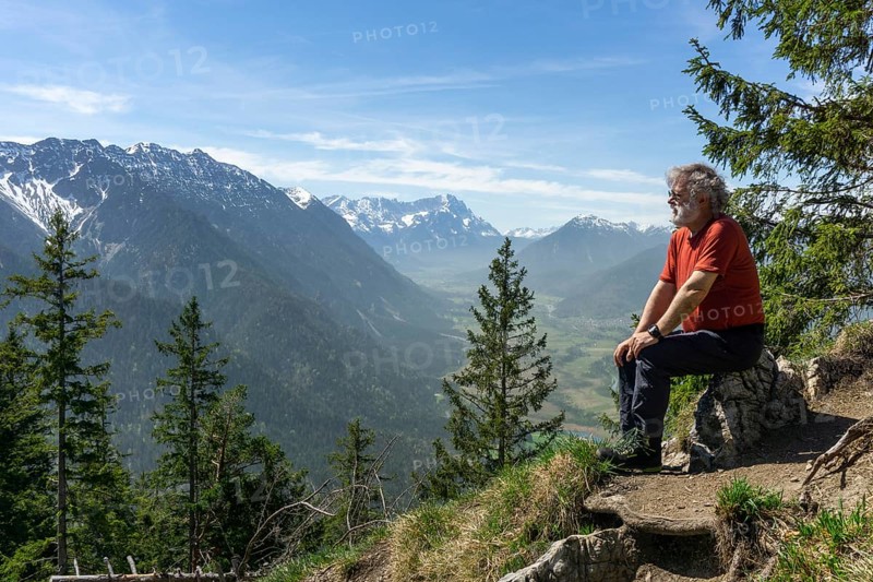 Hiker, senior citizen, 66, resting on the summit of the Osterfeuerkopf with a view of the Zugspitze, Eschenlohe, Estergebirge, Upper Bavaria, Bavaria, Germany, Europe