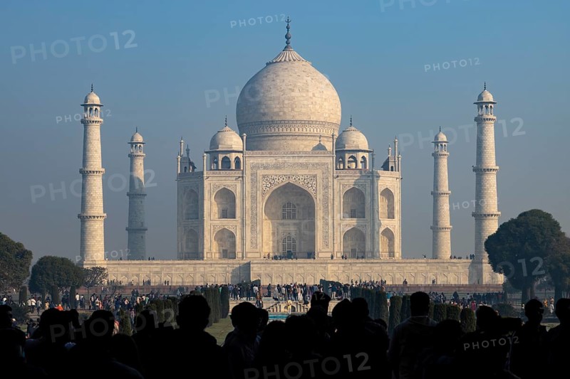 Taj Mahal, the mausoleum built for Mumtaz Mahal by her husband, the Mughal emperor, Shah Jahan. Wonder of the World, a UNESCO World Heritage Site, famous landmark and tourist attraction. View from the gateway with visitors watching and photographing. Winter morning light, clear blue sky. Agra, Uttar Pradesh, India, Asia