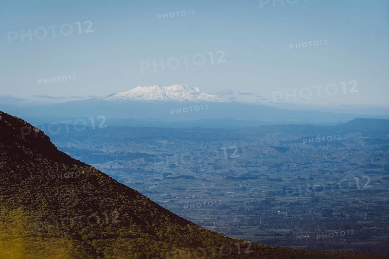 Snow-capped mountains on the horizon, hills in the foreground and blue sky, Mount Taranaki, New Zealand, Oceania