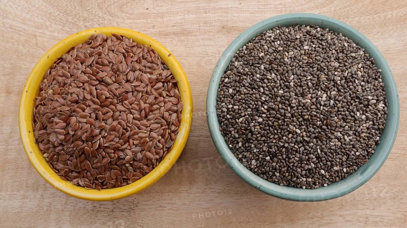 Chia Seeds (Salvia hispanica) vs Flaxseeds (linseeds) in Bowls on Wooden Background, Flat Lay Photo
