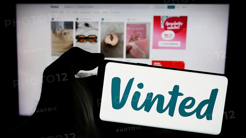 Stuttgart, Germany, 03-17-2024: Person holding mobile phone with logo of online secondhand marketplace company Vinted in front of business web page. Focus on phone display, Europe