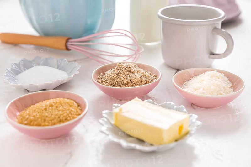 Baking ingredients and kitchen utensils on white wooden background