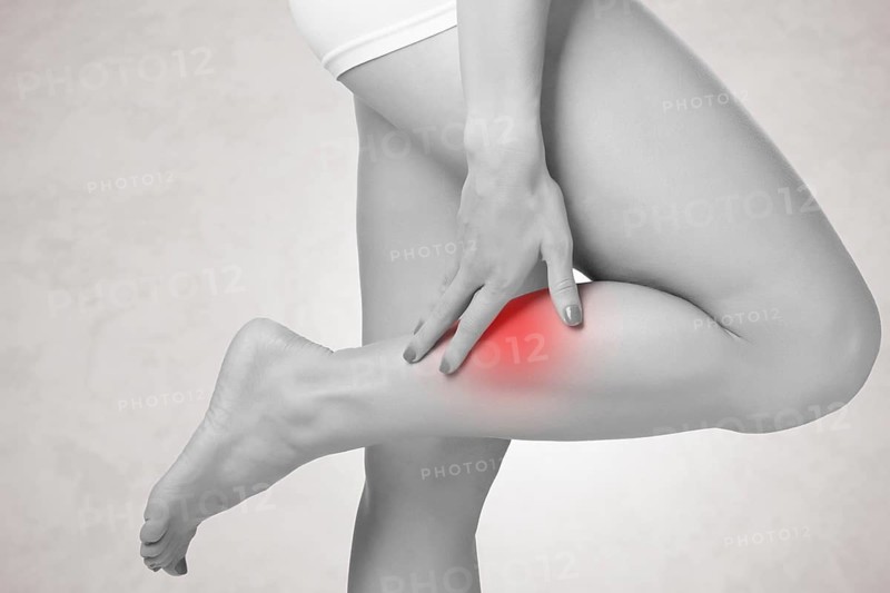 Female with pain in her lower leg, isolated in grey