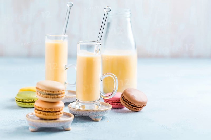 Assorted delicious French macarons with egg liqueur or eggnog on blue background
