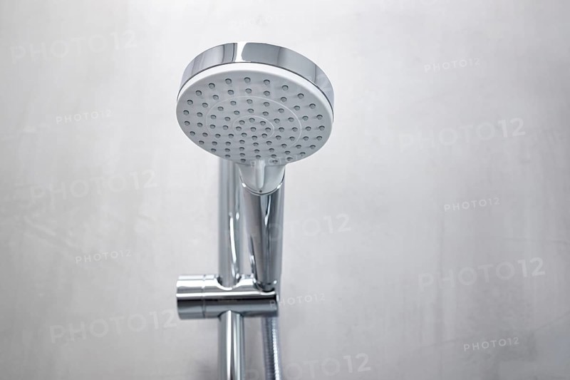 Shower head on a gray microcement wall of a modern bathroom