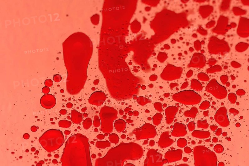 Macro of drops of red food color on cooking oil with back light through red photography gel