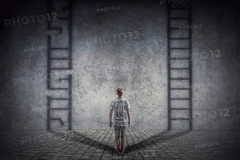 Person stands in front of a wall casting two ladder shadows with one broken on the left and another ready to use on the right. Dilemma and choice concept between good and bad