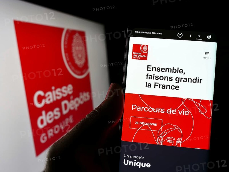 Stuttgart, Germany, 03-12-2023: Person holding smartphone with webpage of Caisse des Depots et Consignations (CDC) on screen in front of logo. Focus on center of phone display, Europe