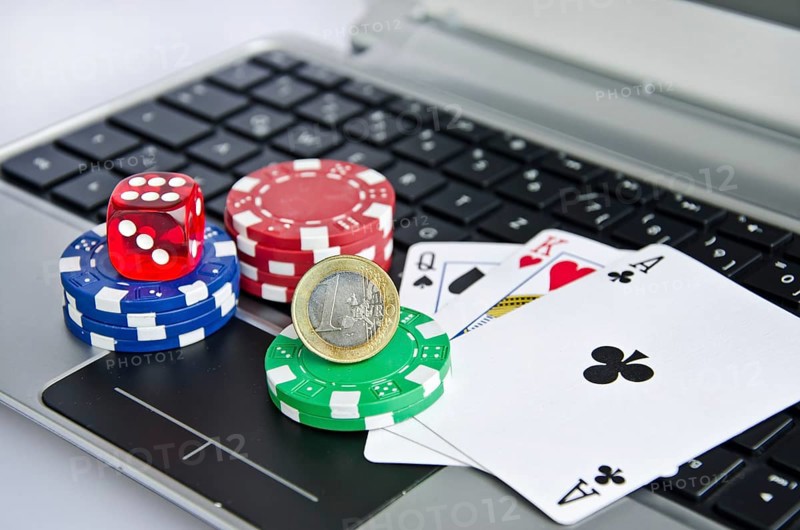 Playing cards, casino chips and Euro coin on a laptop keyboard symbolizing online gambling