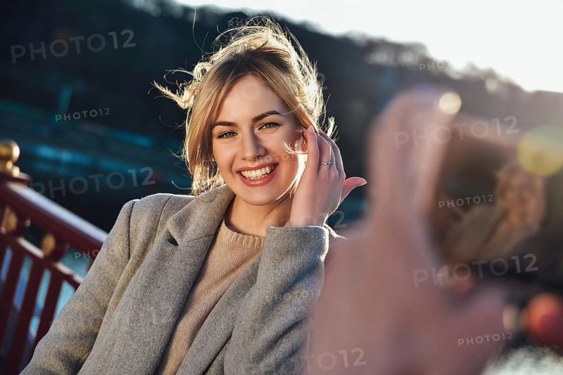 A man make a portrait of happy smiling woman standing on the bridge on sunny summer or spring day outdoor