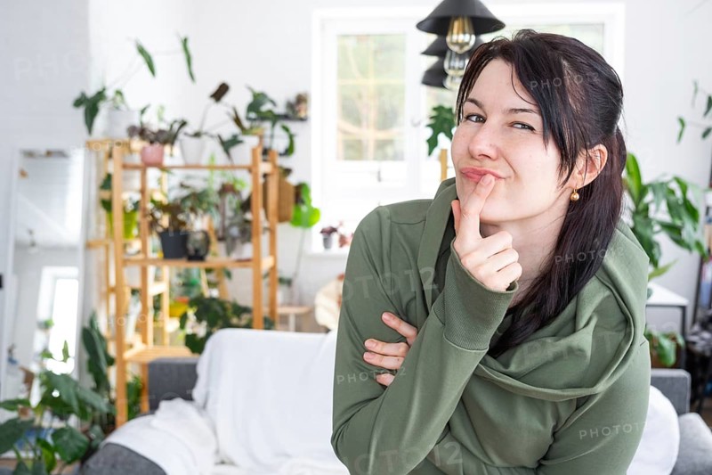 Thoughtful emotions of a woman in her home in a bright modern interior with home plants. Portrait of a dreamy
