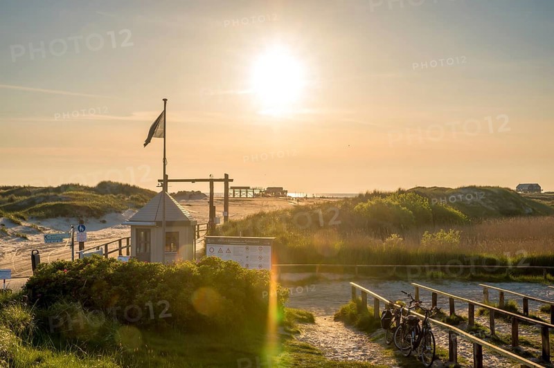 Beach access in the dunes with map house and bicycle stands backlit by the evening sun, St. Peter Ording, Schleswig Holstein, Germany, Europe
