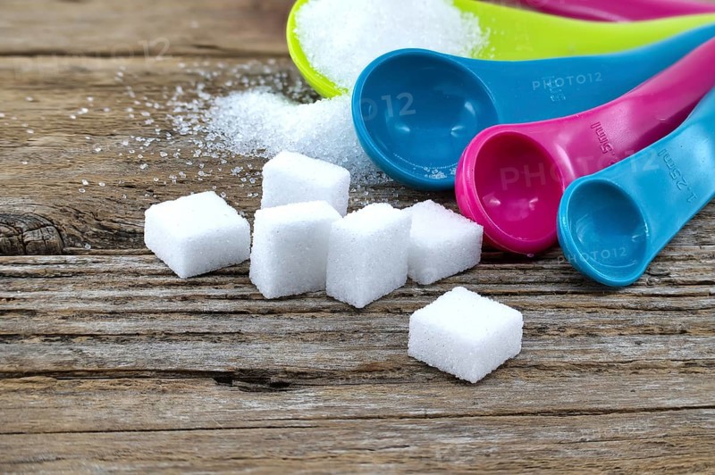 Array of sugar presentations on a wooden table, showcasing sugar cubes and granulated sugar