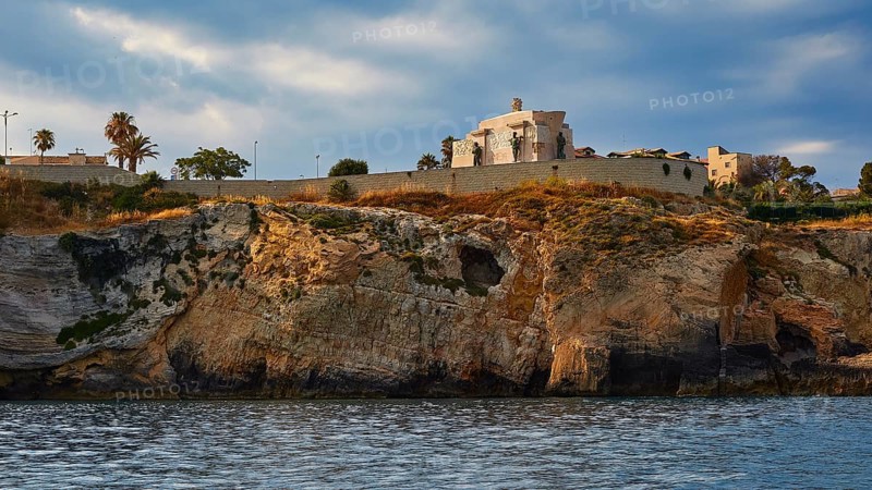 Building on a cliff under a cloudy sky next to the sea, boat trip around the island of Ortigia, Isola di Ortigia, Syracuse, Sicily, Italy, Europe