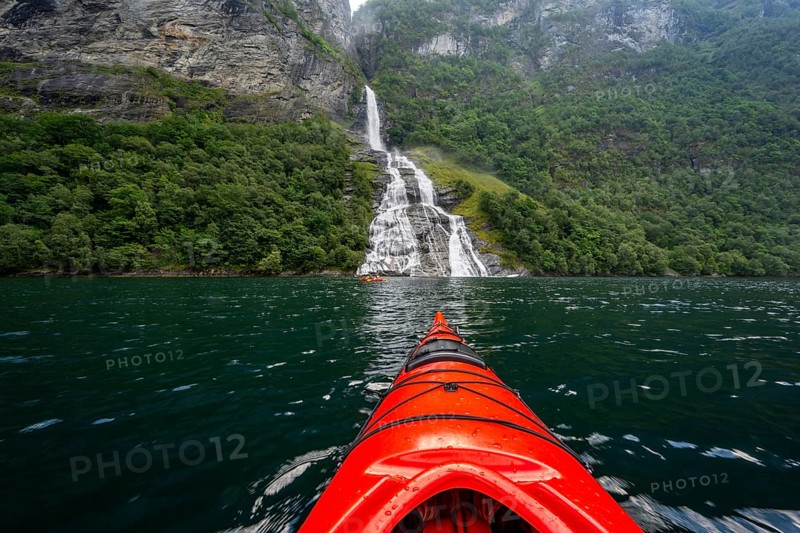 Kayak trip on the Geirangerfjord at the Freier waterfall, tip of a red kayak in the fjord, atmospheric fjord landscape, first person view, near Geiranger, Møre og Romsdal, Norway, Europe